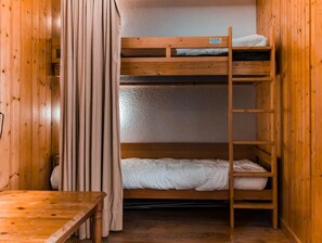 A bunk bed room with wooden walls and a wooden table.