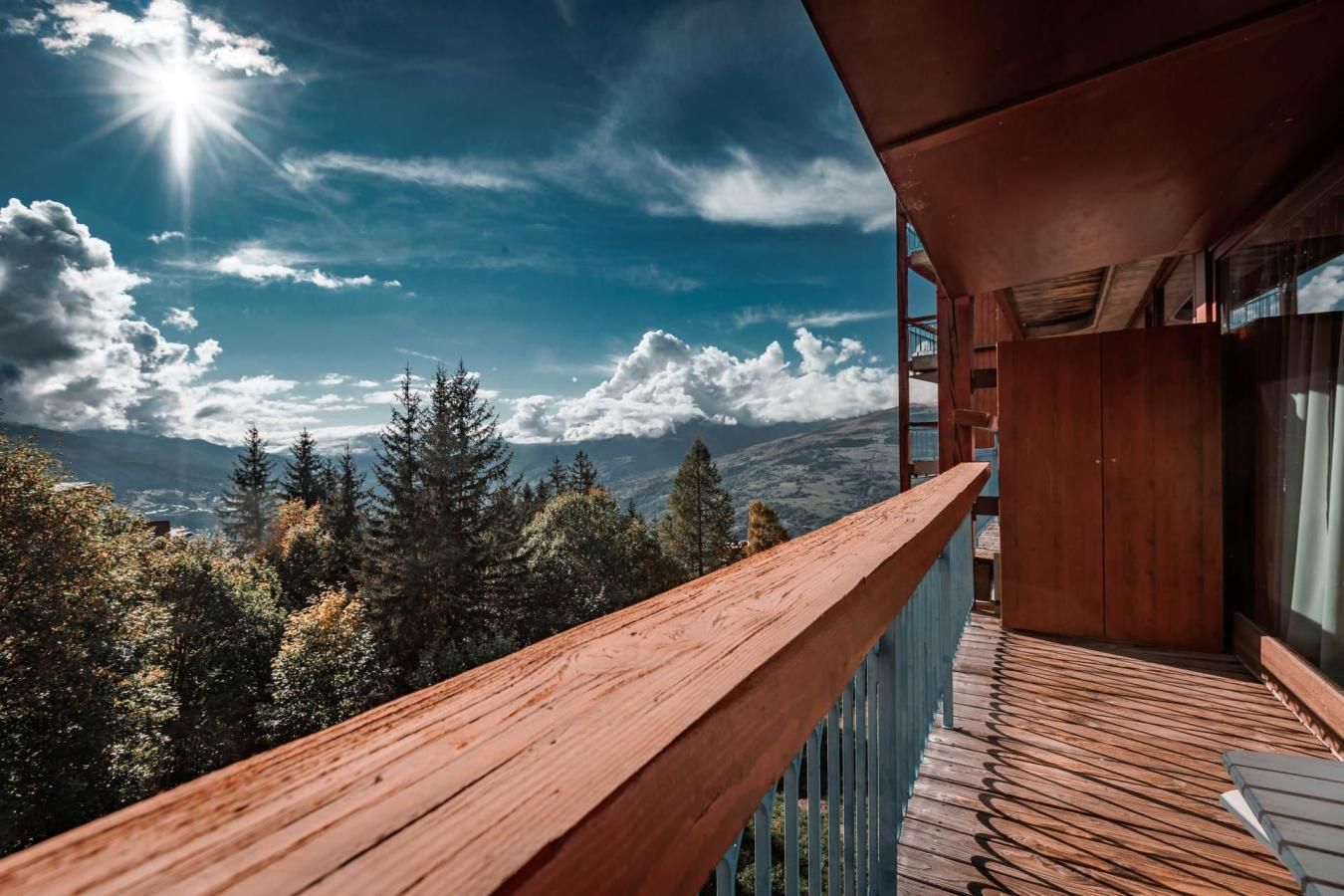A balcony with a wooden railing overlooking a mountainous landscape.