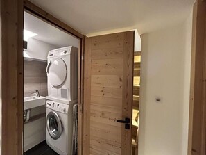 Un cuarto de lavandería con lavadora y secadora, puerta de madera y un lavamanos pequeño.