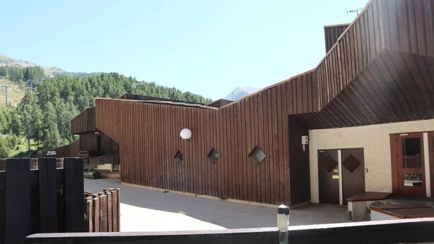 Un bâtiment moderne doté d’une façade en bois, d’un balcon et d’une porte avec une enseigne.