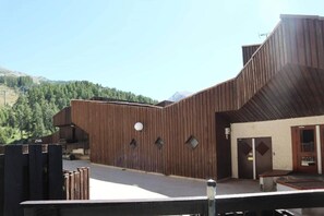 Un edificio moderno con fachada de madera, un balcón y una puerta con un letrero.