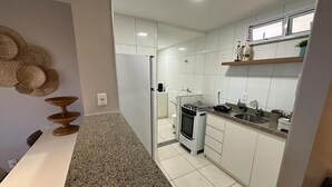 A modern kitchen with white cabinets, a granite countertop, and a stainless steel stove. - Porto Beach Conforto e Lazer a 200m do B Park (Aquiraz)