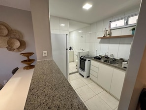 Una cocina moderna con armarios blancos, encimera de granito y estufa de acero inoxidable.