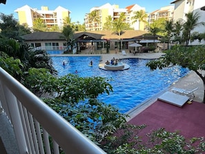 A swimming pool with a circular hot tub, surrounded by palm trees and a building with balconies. - Porto Beach Conforto e Lazer a 200m do B Park (Aquiraz)