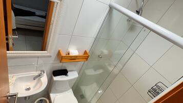 A compact bathroom with a glass-enclosed shower, a sink, and a toilet.