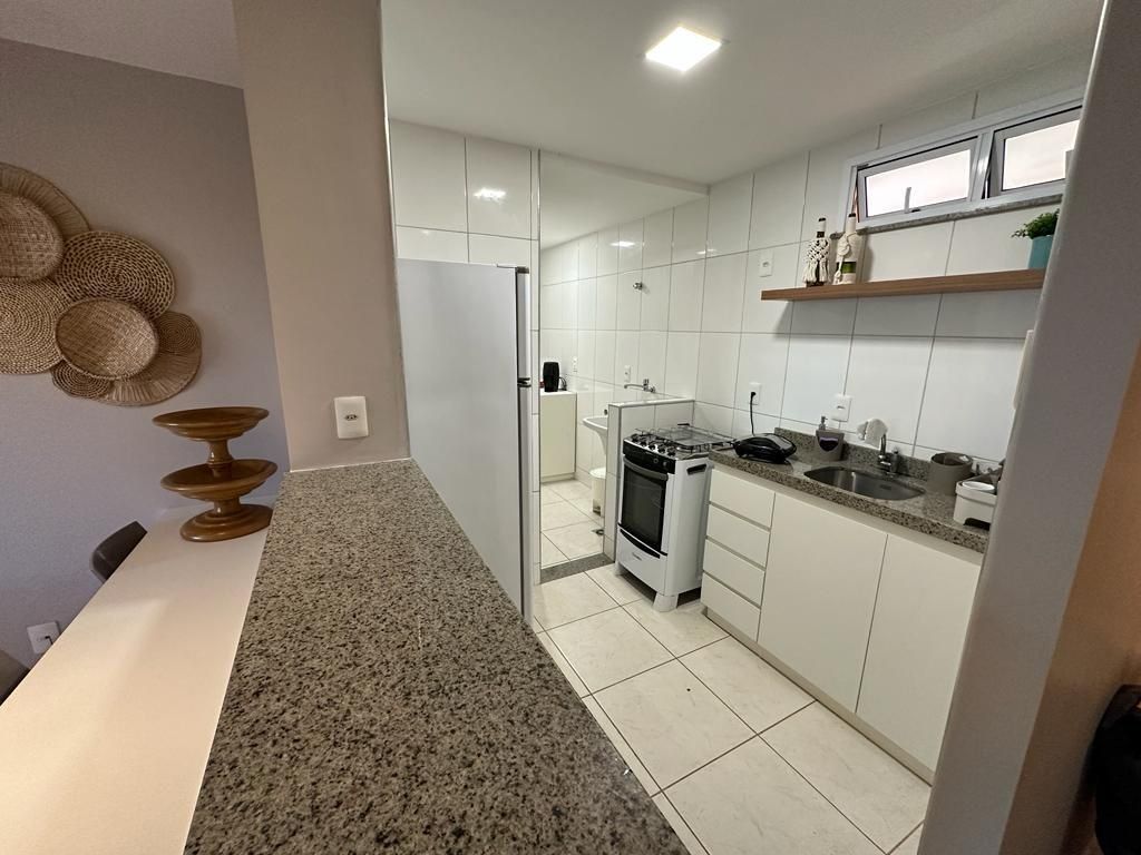 Una cocina moderna con armarios blancos, encimera de granito y estufa de acero inoxidable.