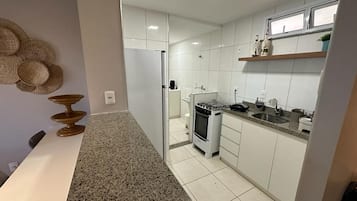 Una cocina moderna con armarios blancos, encimera de granito y estufa de acero inoxidable.