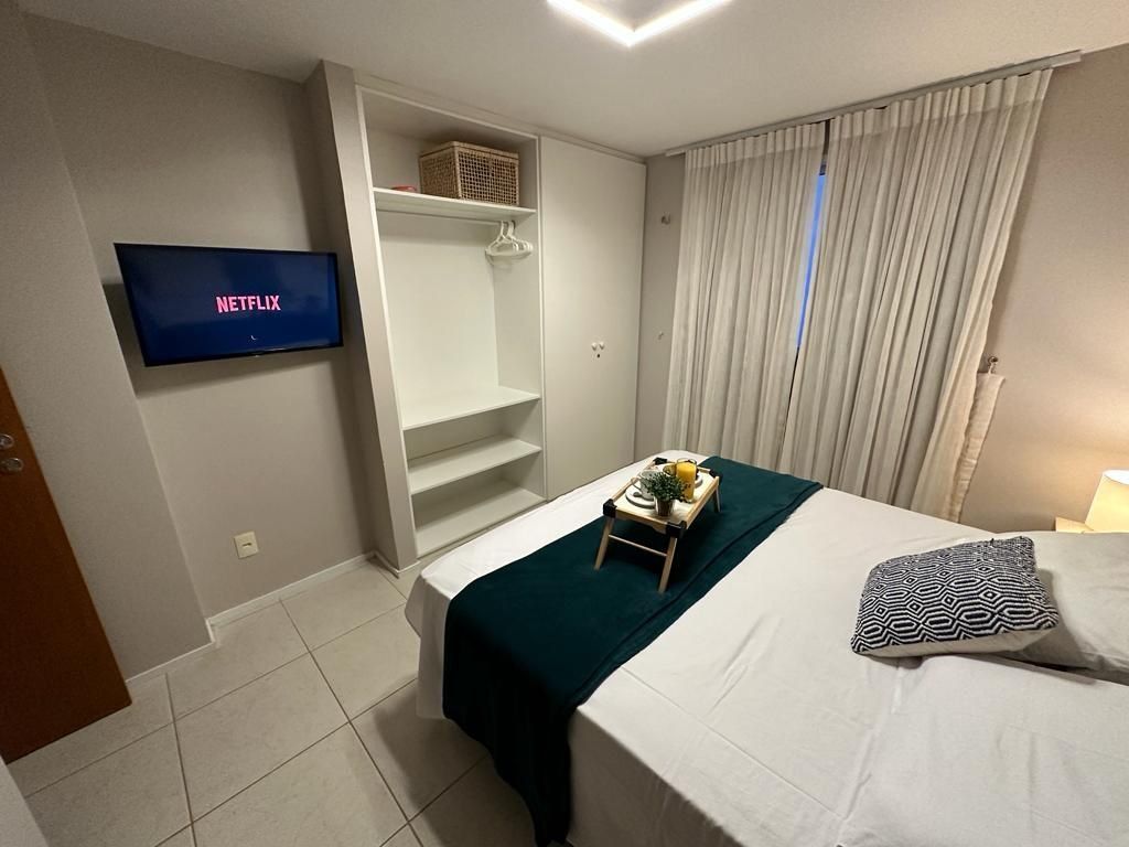 A hotel room with a bed, a TV displaying 'NETFLIX', a wardrobe, and a window with curtains.