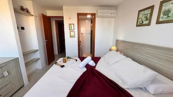 A hotel room with a bed, a bedside table, a lamp, and a wall-mounted air conditioner.