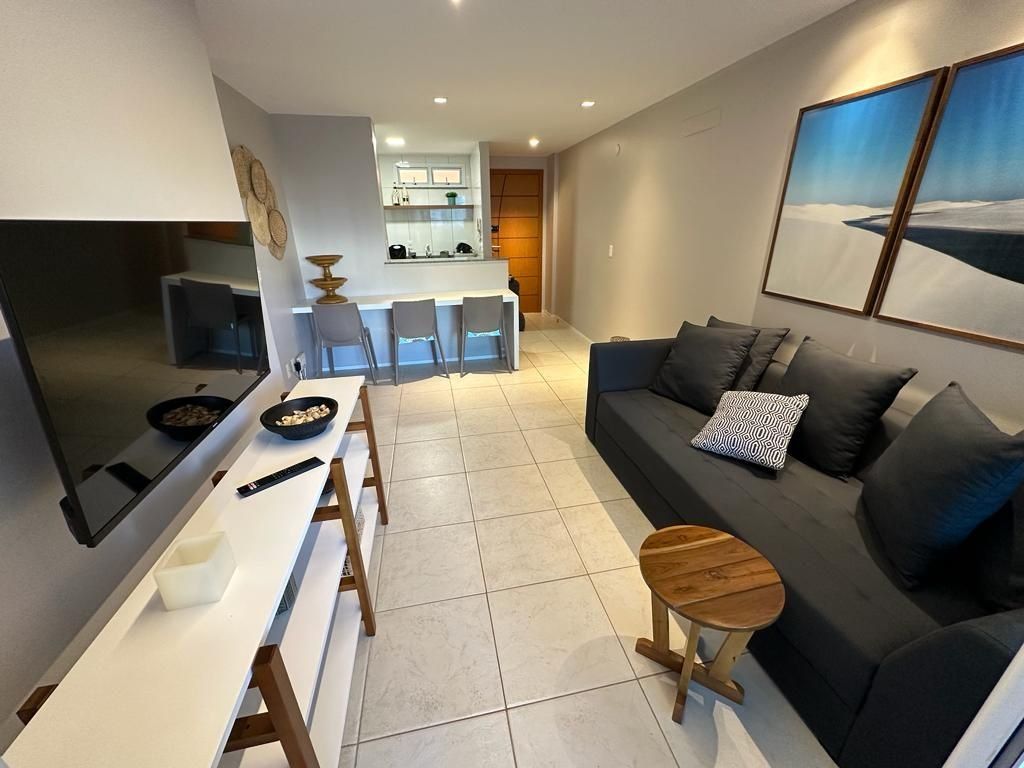 Una sala de estar moderna con sofá, una mesa de comedor y una cocina al fondo.