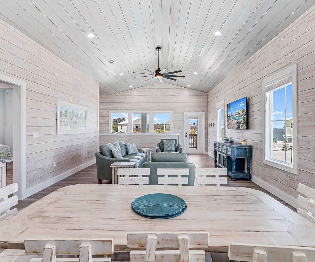 A spacious room with a high ceiling, wooden walls, and a central seating area with a sofa and chairs.