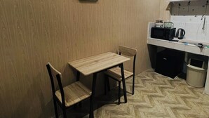 A small kitchenette with a microwave, toaster, and kettle. There is a wooden table with two chairs and a framed sign on the wall. - 83 F. Bautista St (Quezon City)