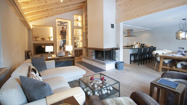 A spacious living room with a fireplace, a sofa set, a coffee table with decorative items, and a dining area with chairs and a table.