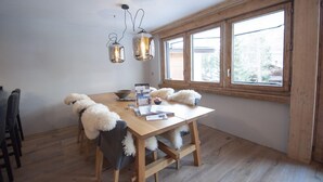 A dining area with a wooden table, chairs, and hanging light fixtures.