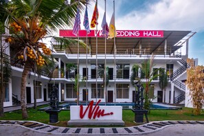 Un salón de bodas con un diseño arquitectónico moderno, que destaca por su entrada imponente y varias banderas.