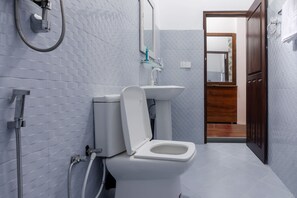 Un baño moderno con inodoro blanco, lavamanos de vidrio y ducha.