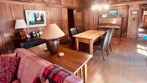 A cozy room with wooden paneling, a dining table with chairs, a sofa with a plaid throw, and a lamp. - Wildwood a great family house Sleeps up to 10!  Walk to trails! (Inverness)