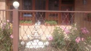 A gated courtyard with a fountain, potted plants, and a building with multiple windows in the background.