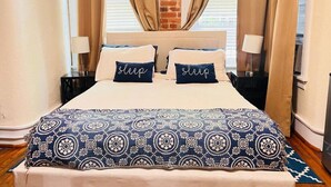 A neatly made bed with a patterned bedspread and two pillows with the word "sleep" on them.