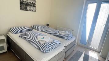 Una habitación con dos camas, un radiador, un cuadro en la pared y una ventana con persianas.