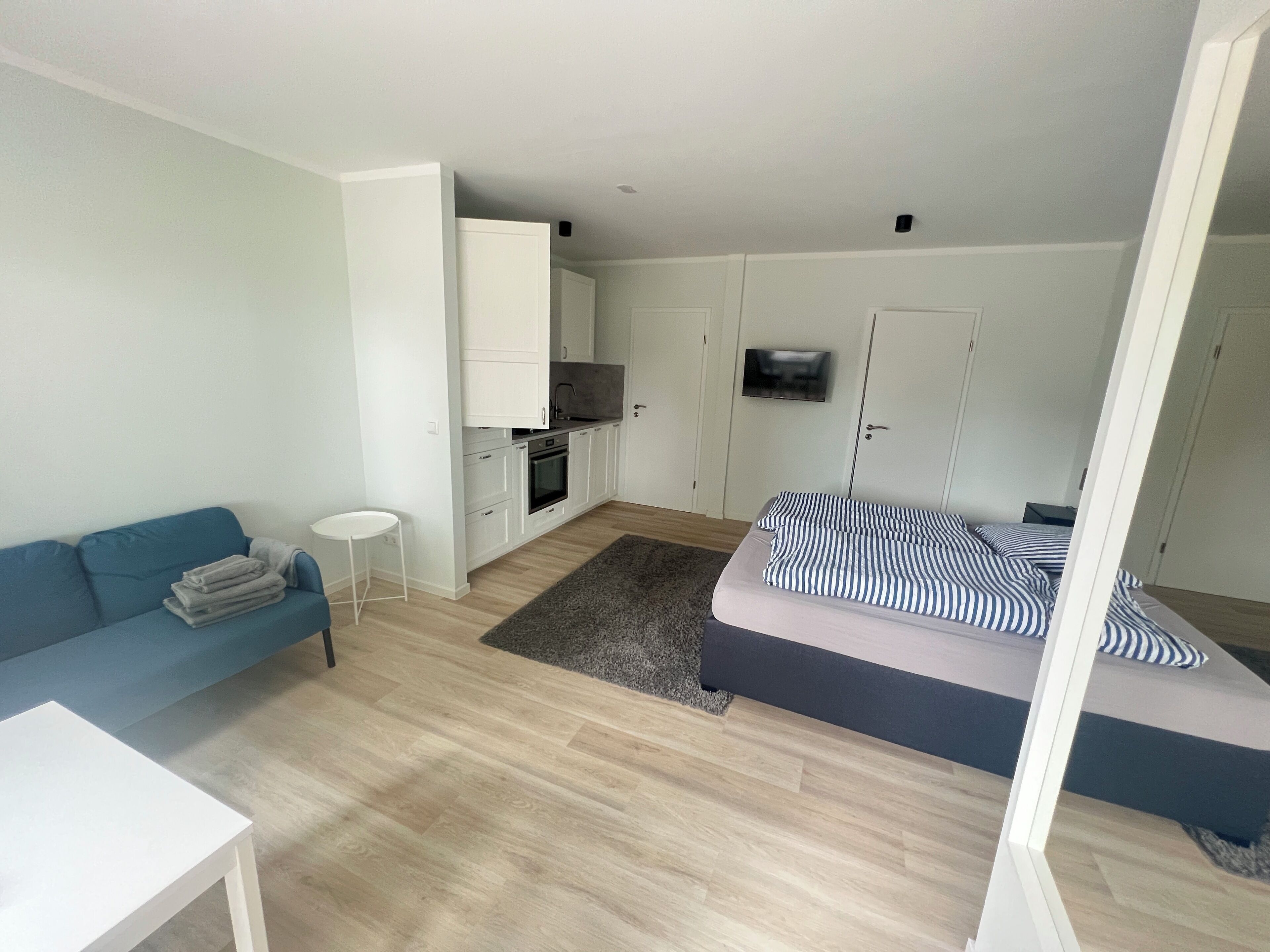 A compact living space with a kitchenette, a sofa, a bed, and a small table.