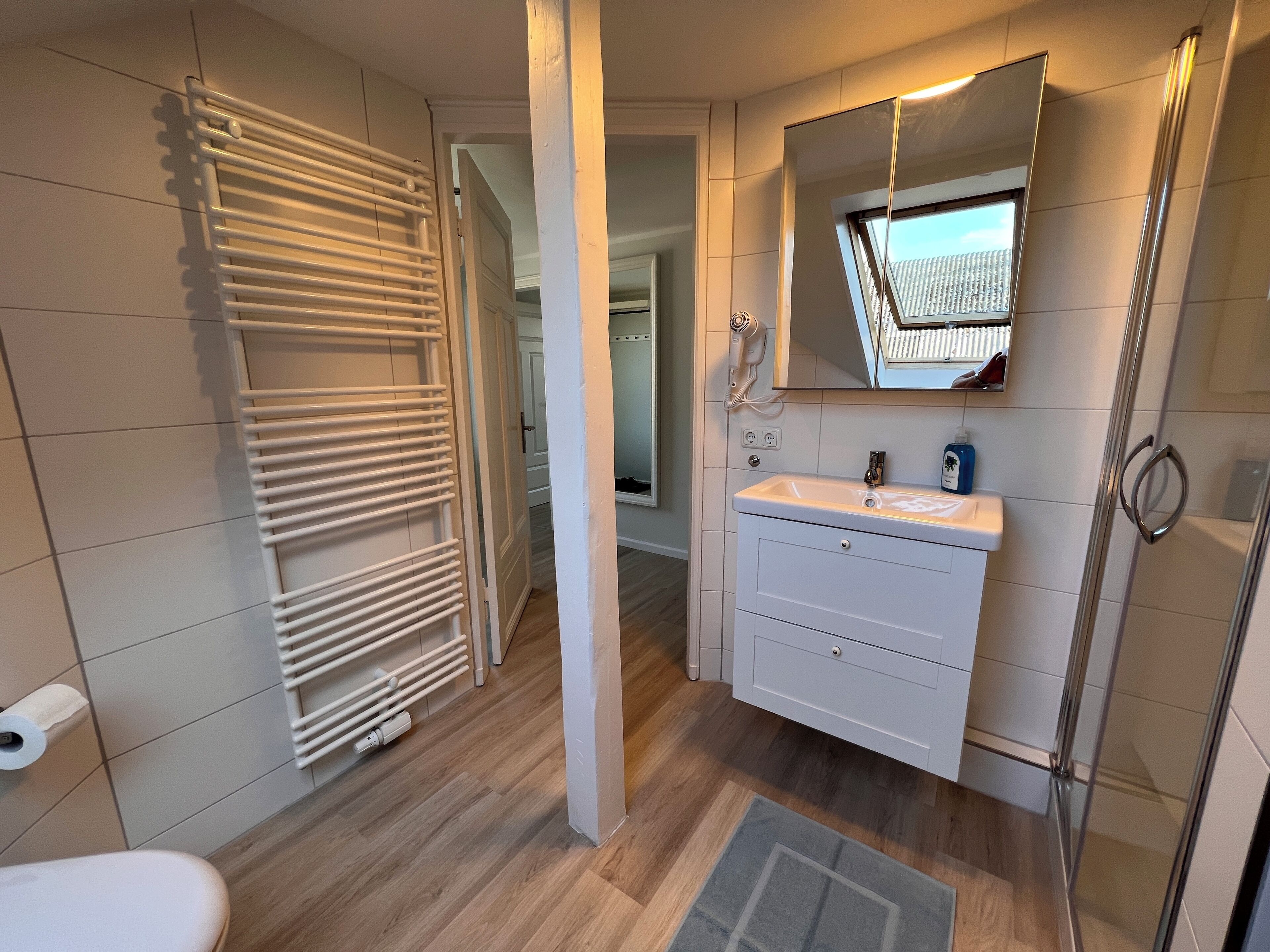 A modern bathroom with a white vanity, a glass shower enclosure, and a towel rack.