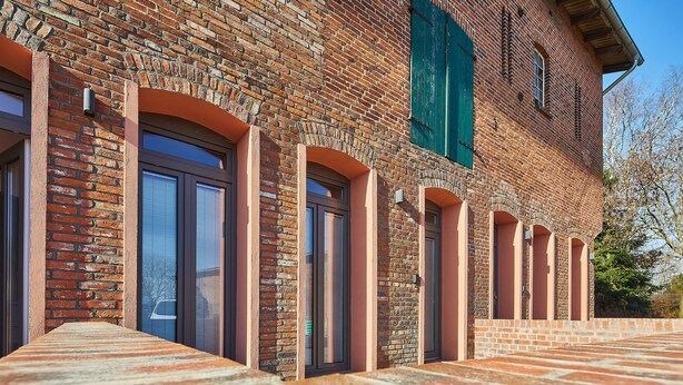 Un bâtiment en briques doté de plusieurs portes en arc et d’un trottoir pavé.