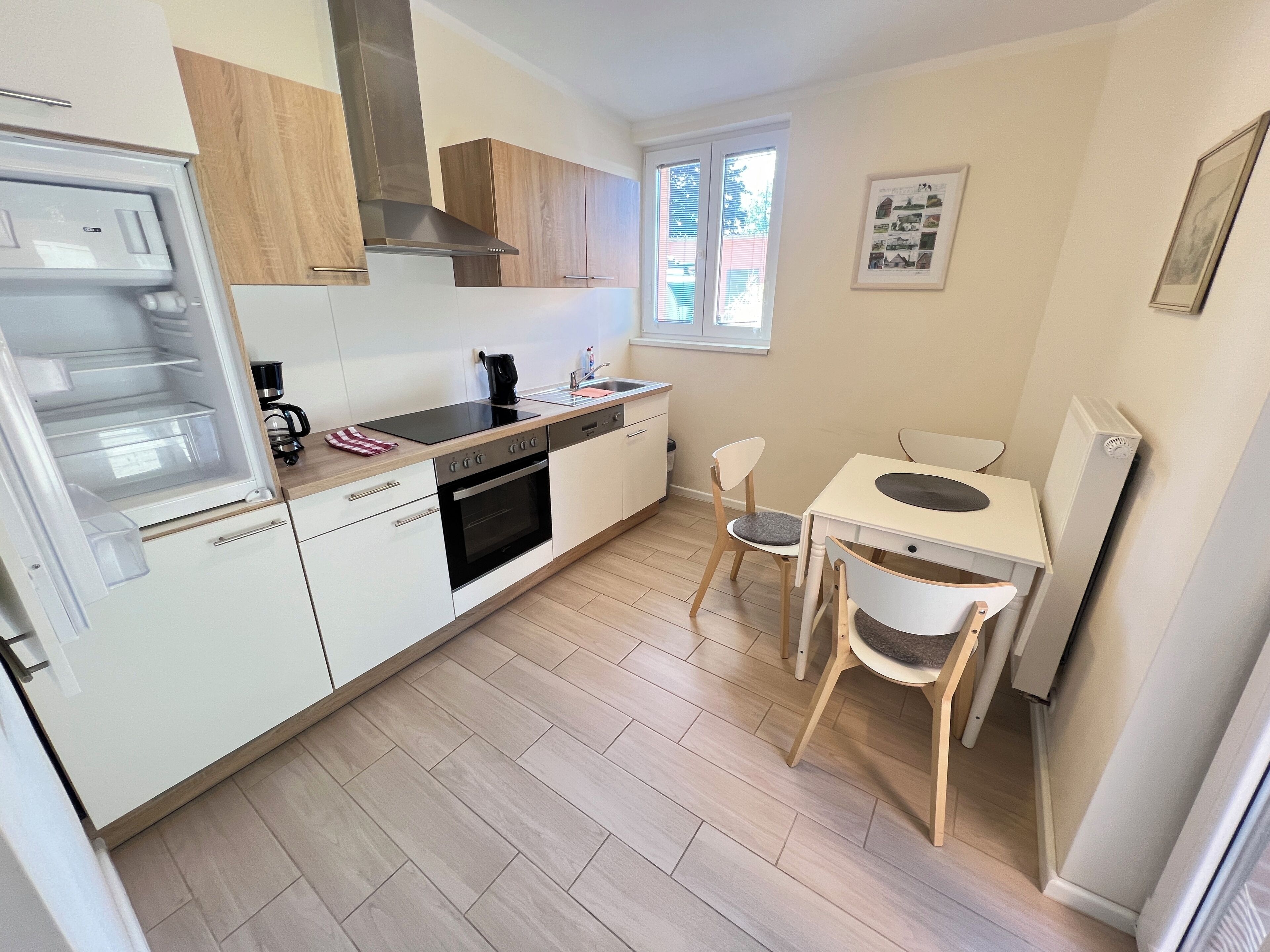 A compact kitchen with white cabinets, a black stove, and a small dining area with two chairs.