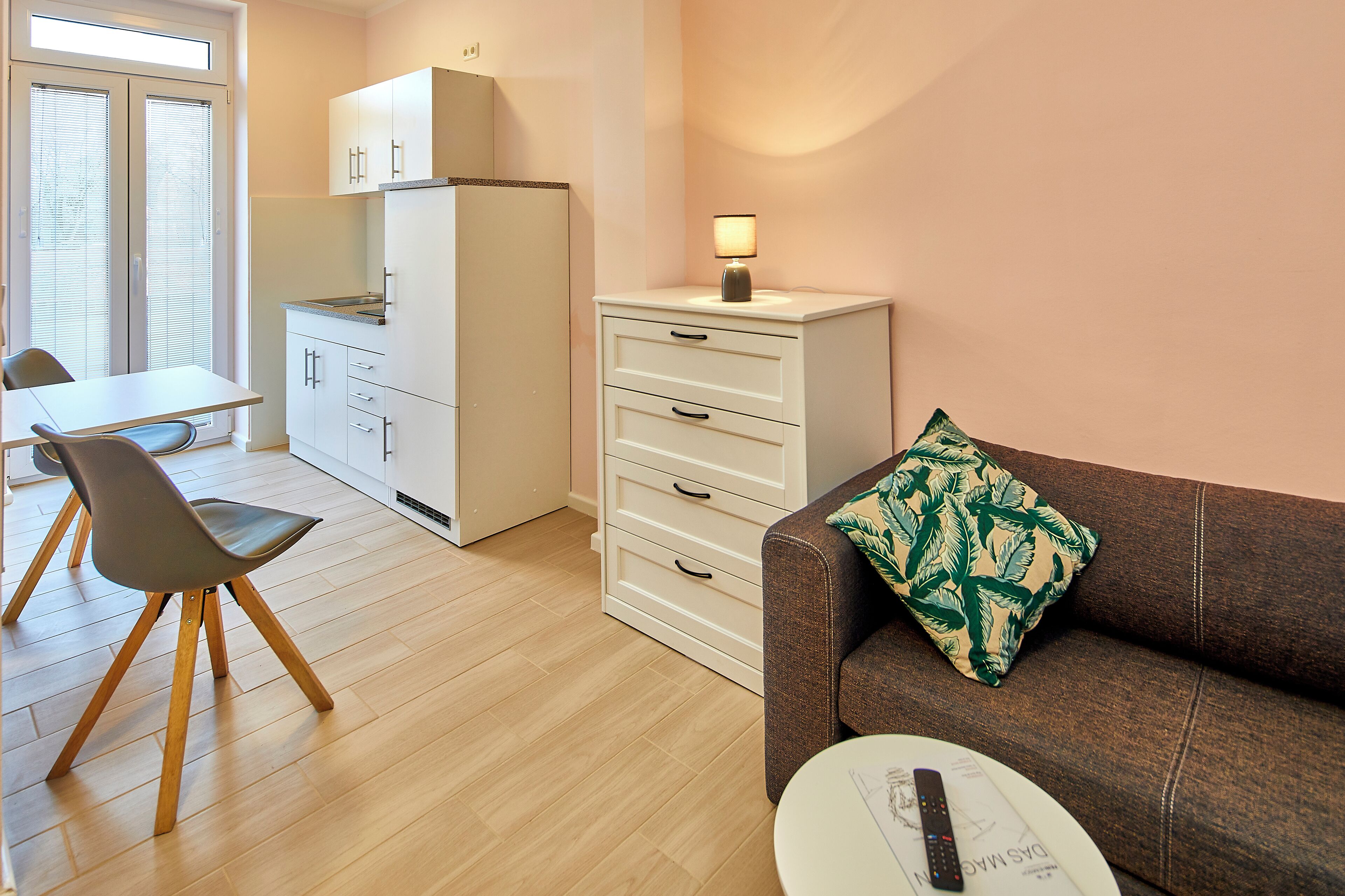 Un espacio habitable compacto con kitchenette, zona de comedor y sala de estar con sofá y mesa.