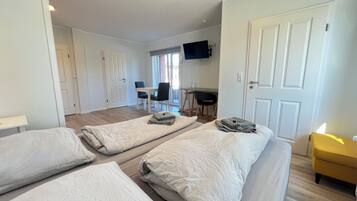 A room with two beds, a desk, a chair, and a TV.