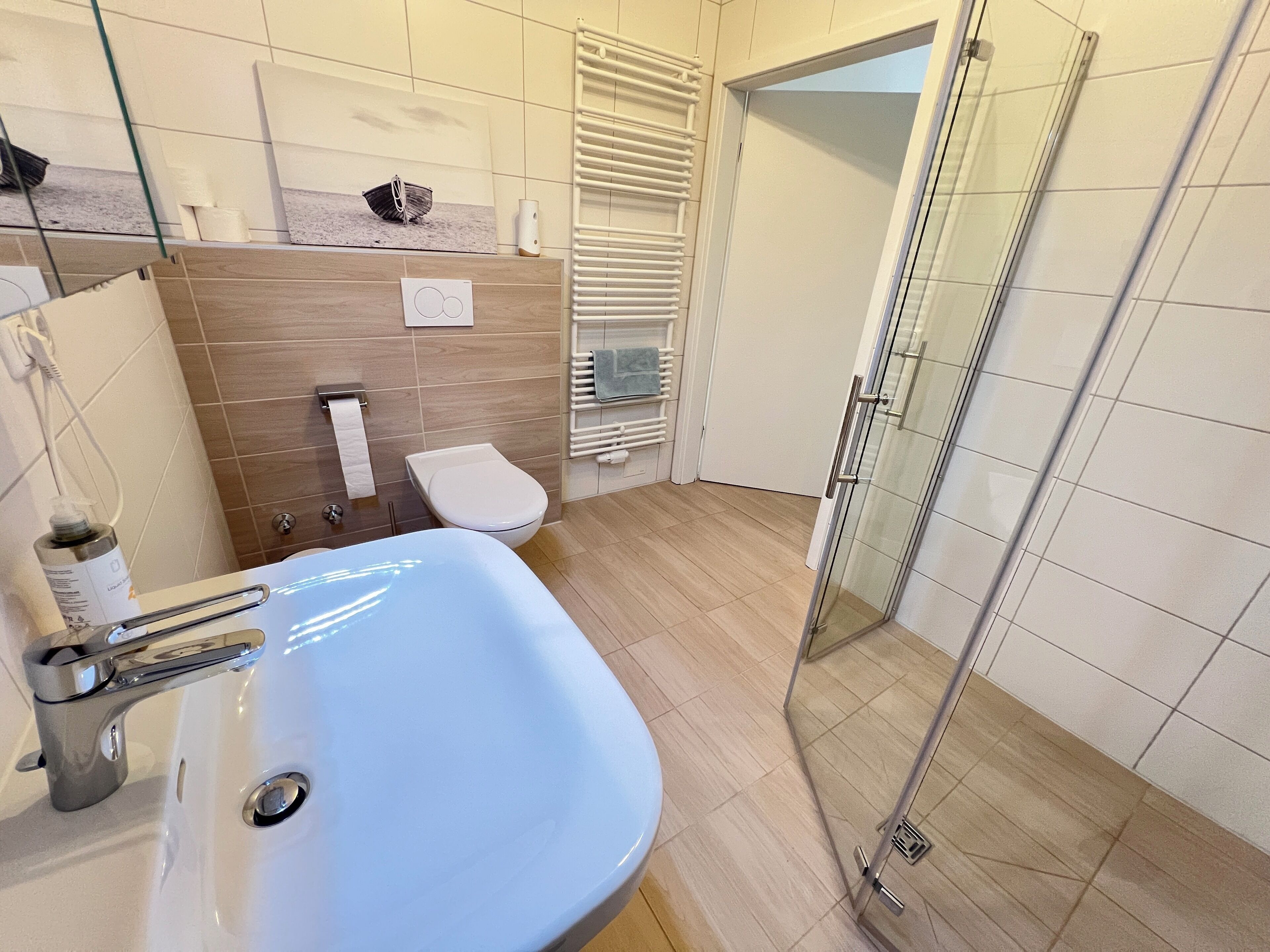 Een moderne badkamer met een wit wastafelmeubel, toilet en douchecabine met glazen wanden.