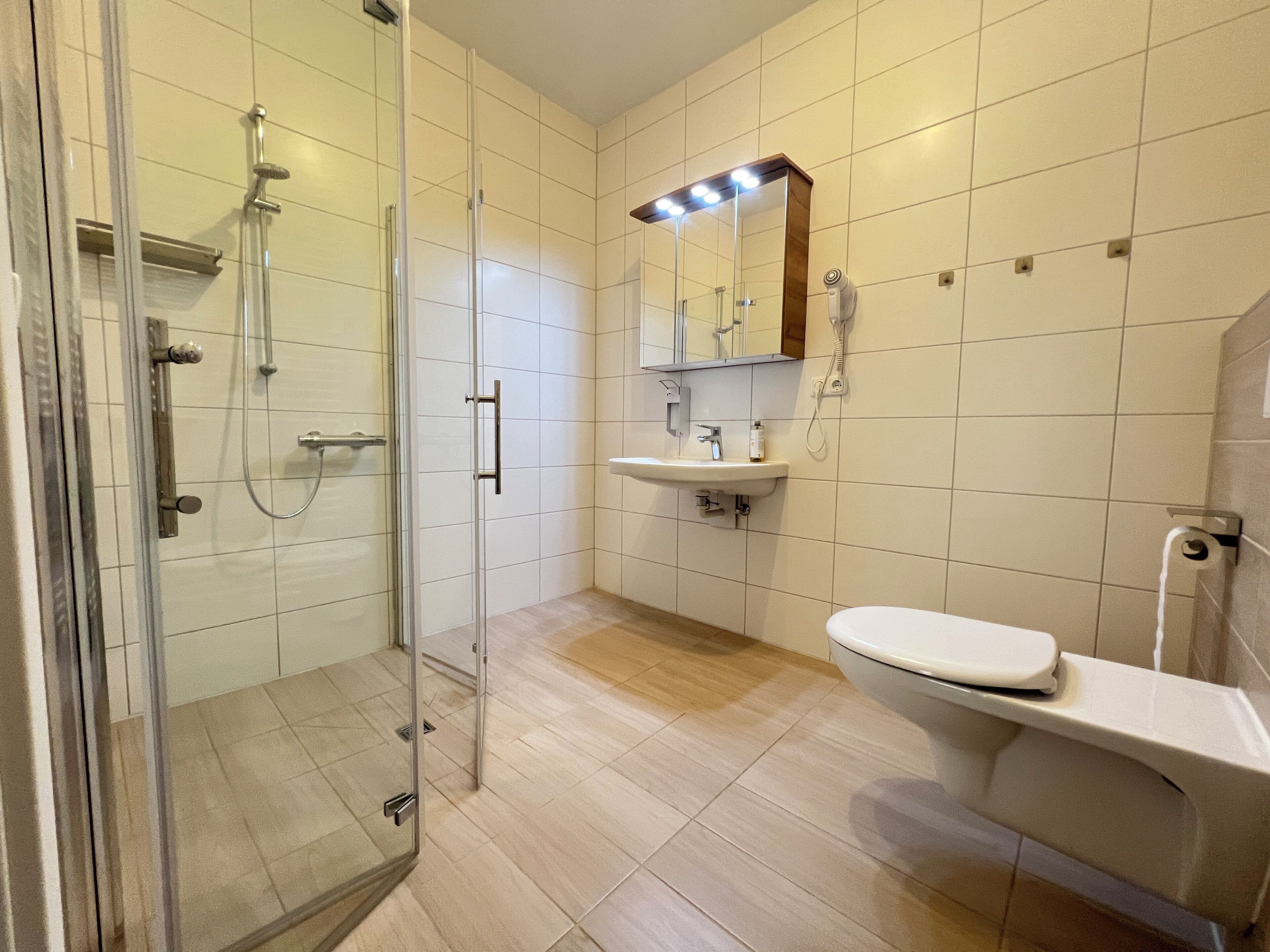 Un bagno moderno con box doccia in vetro, lavandino e WC.