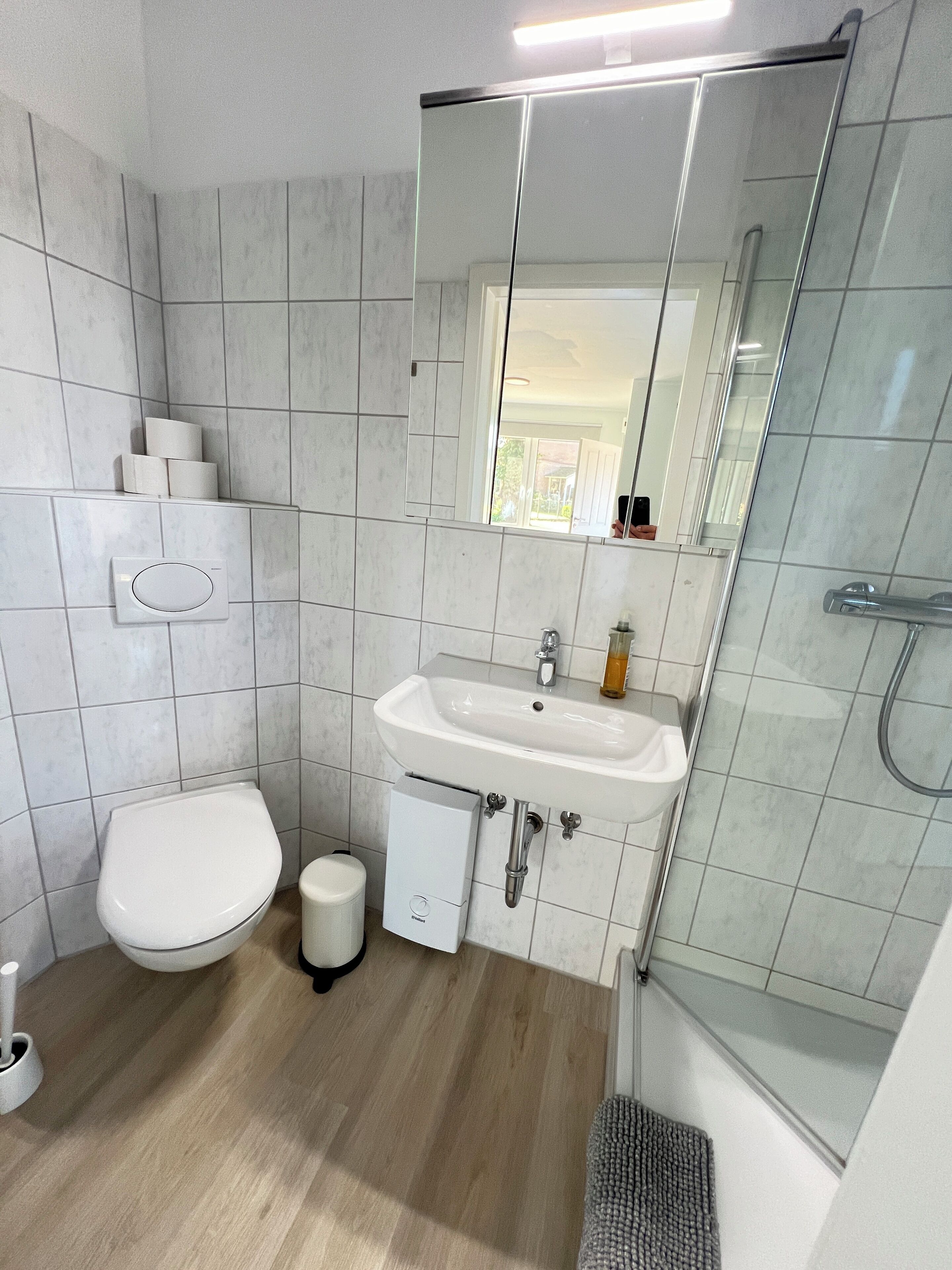 A modern bathroom with a toilet, sink, and glass shower enclosure.