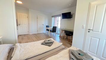 A hotel room with a bed, a desk, and a TV mounted on the wall.