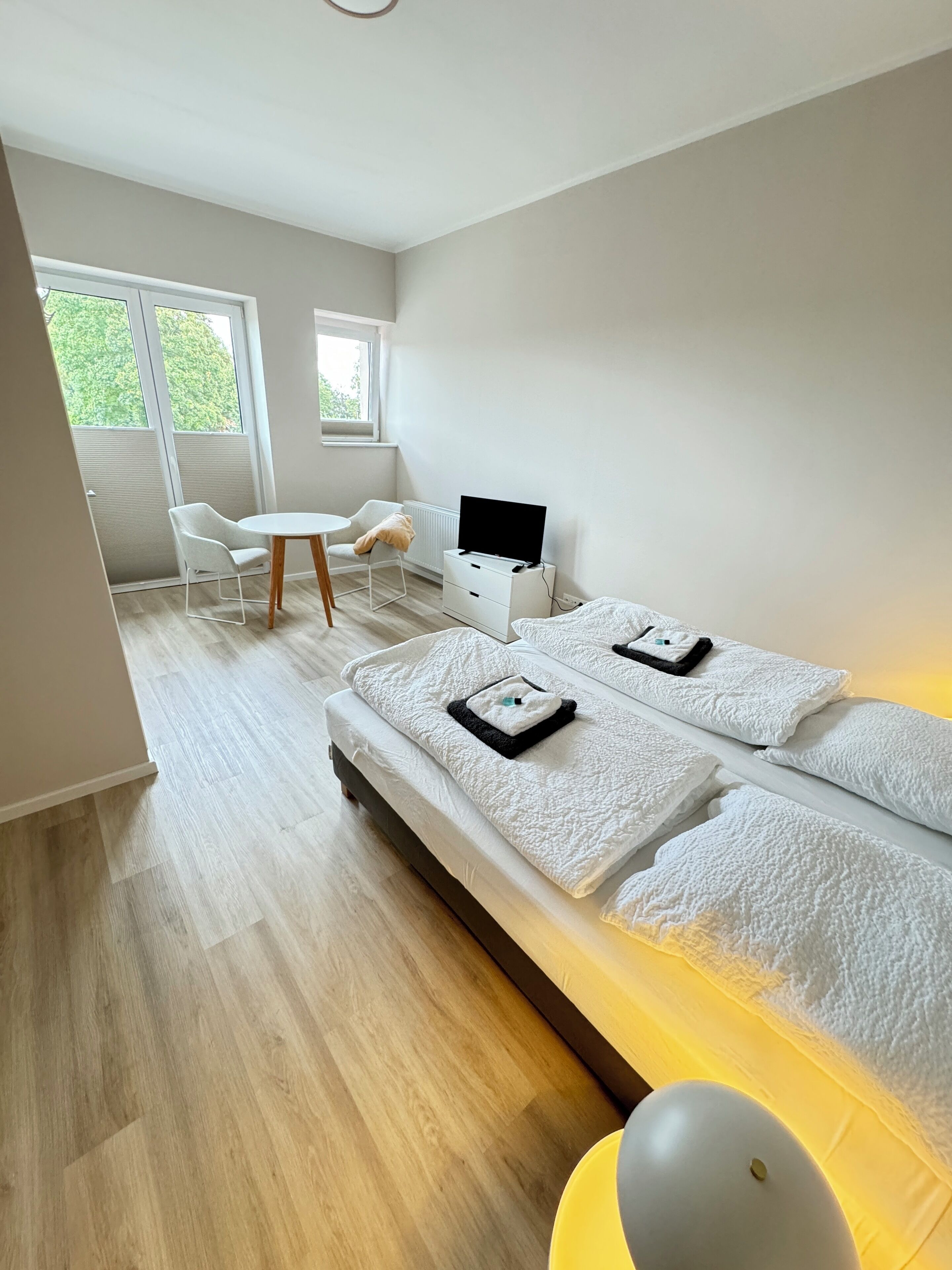 A modern hotel room with a large bed, a desk, and a chair.
