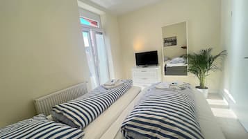 Een hotelkamer met twee bedden, een televisie, een spiegel en een potplant.