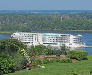 A large, multi-story river cruise ship with balconies, docked at a river port.