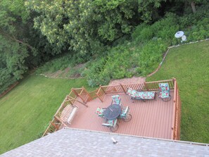Une terrasse dotée de mobilier d’extérieur, entourée d’un jardin et d’arbres.