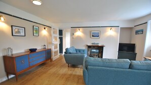 Un salon avec un canapé bleu, un meuble en bois et un téléviseur.