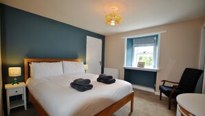 Une chambre à coucher avec un lit, des tables de chevet, une chaise, une fenêtre et un luminaire au plafond.