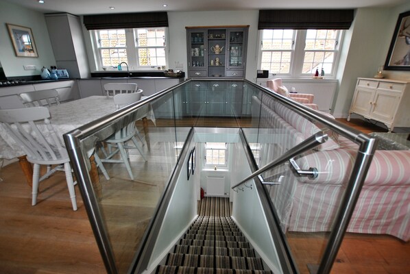 A modern kitchen with a glass staircase leading to a dining area. - The Old Stables- charming cottage, Crail (Crail)
