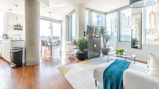 A modern living room with a sofa, coffee table, and potted plants. - 2BR | Gym, Pool | Bellevue | Sophari Towers M (Bellevue)
