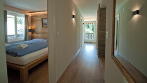 Une chambre d’hôtel avec un lit, une fenêtre, une porte et un couloir menant à un balcon.