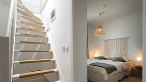 A staircase with woven handrails, a bed with a green throw, a bedside lamp, and a macrame wall hanging. - Villa Sunset with spectacular views (Porec)