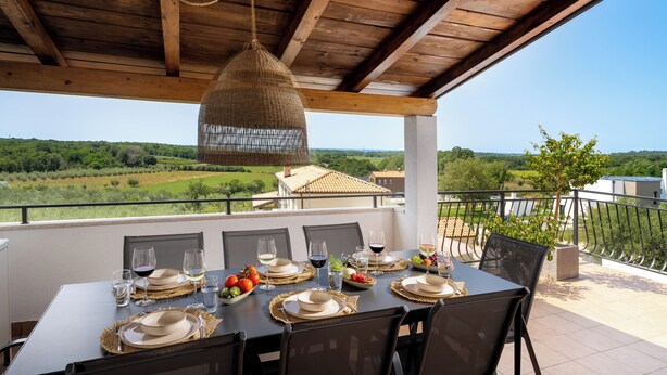 A dining table set for six with plates, glasses, and a bottle of wine, overlooking a scenic landscape. - Villa Sunset with spectacular views (Porec)