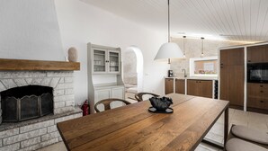 A modern kitchen with a built-in fireplace, wooden dining table, and pendant lighting. - Villa Sunset with spectacular views (Porec)