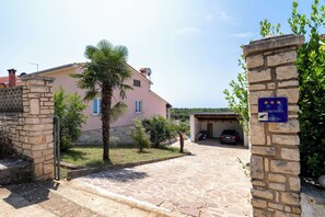 A pink house with a stone gate, a palm tree, and a parked car.
