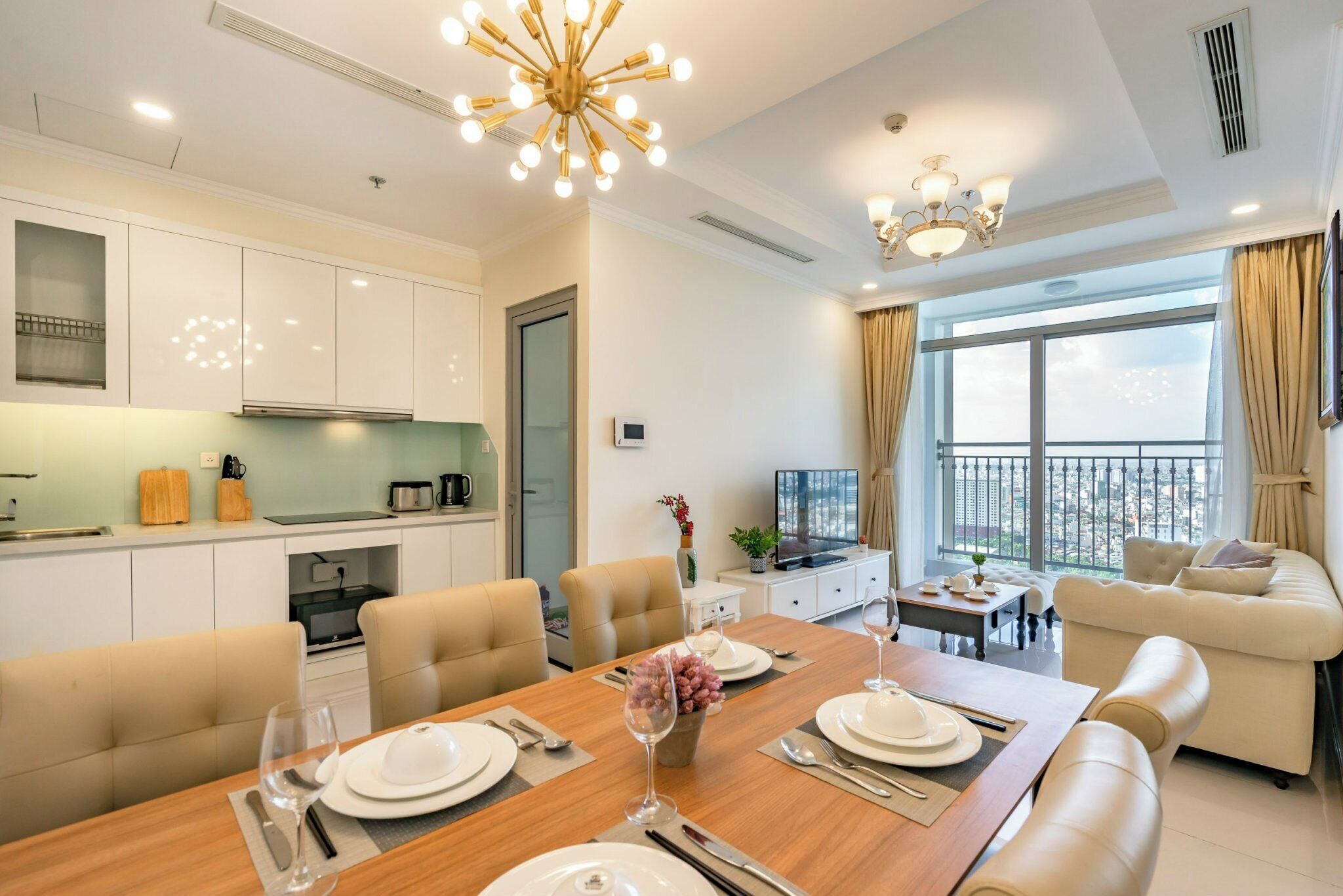 A modern living room with a dining area, a kitchen, and a balcony with a view.