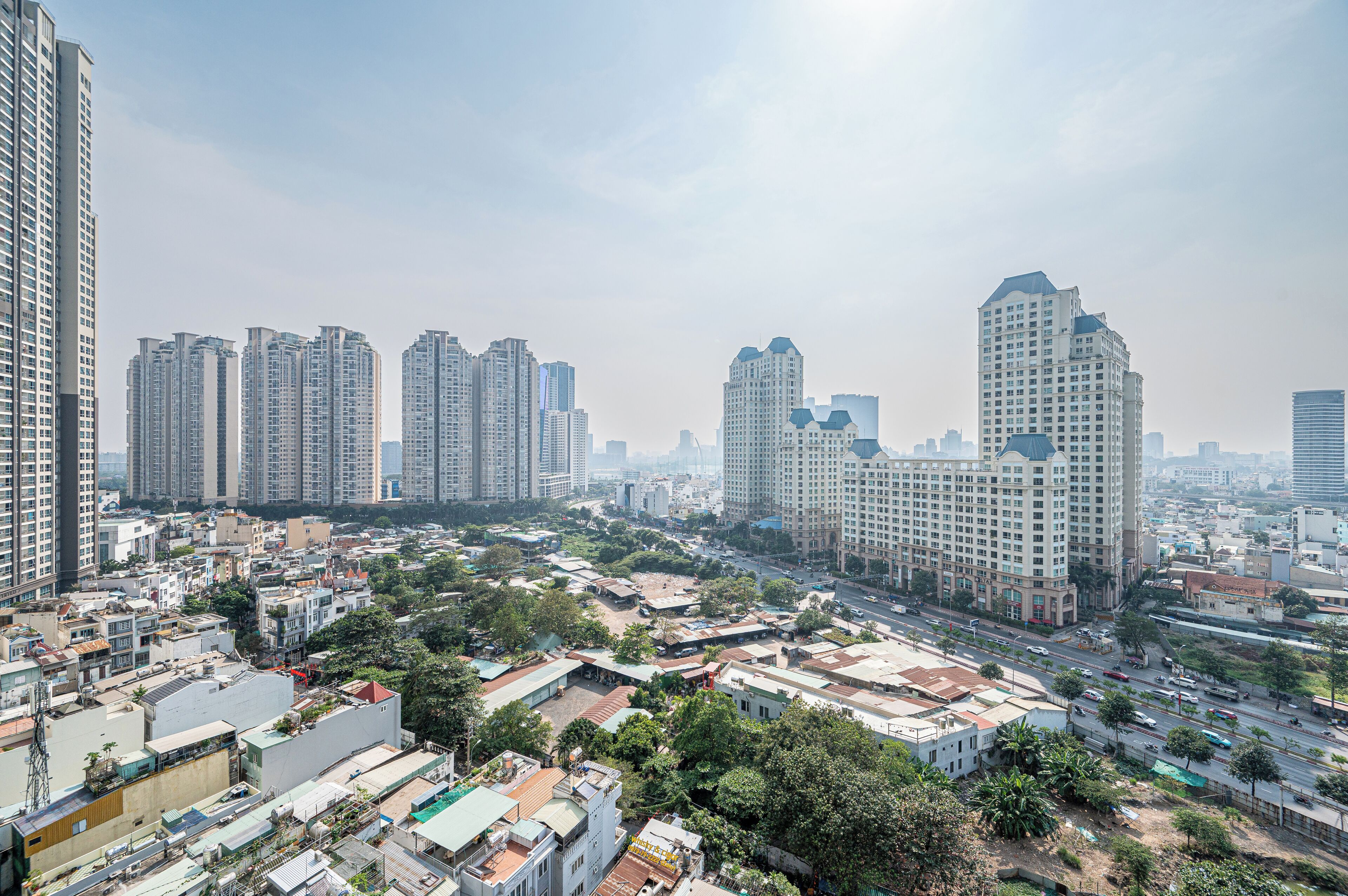 A cityscape with high-rise buildings, a mix of residential and commercial structures, and a busy street with vehicles.