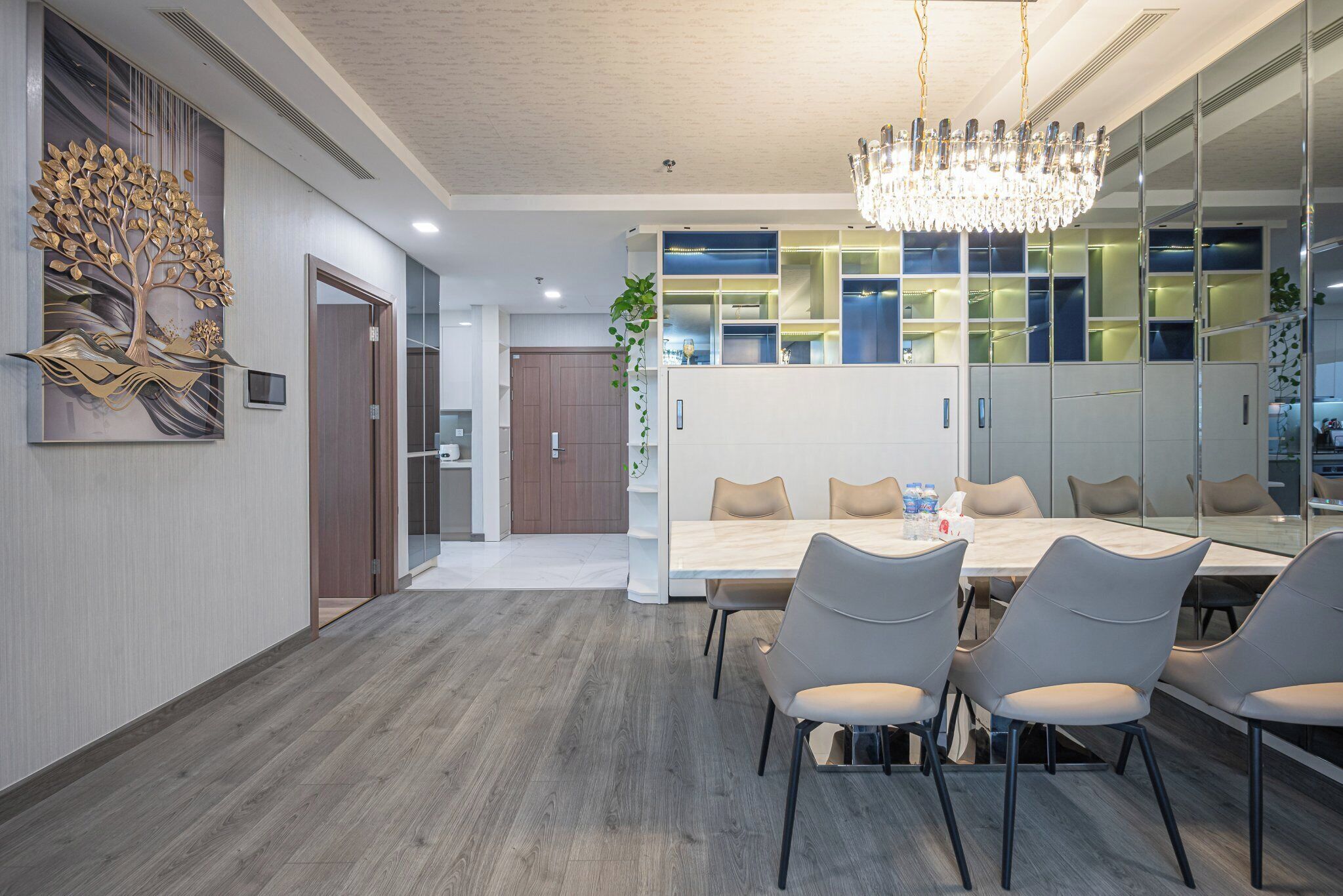 A modern dining area with a large table, chairs, and a chandelier.